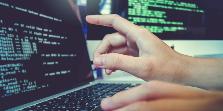 Software-made-in-Italy Immagine di una mano che indica una riga di codice di programmazione su un computer portatile
